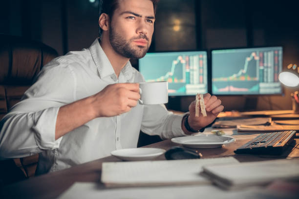 istock Young male trader at office work concept sitting drinking coffee eating sandwich 1146576593