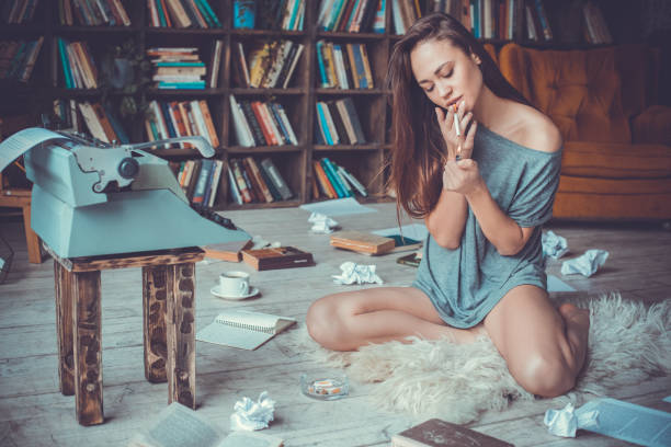 istock Young woman writer in library at home creative occupation lighting cigarette 1146576601