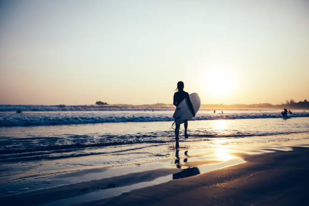 istock Surfer woman walking with surfboard on sunset beach 1146588731
