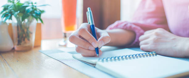 istock Woman hand is writing on a notepad with a pen.Web banner. 1146589684