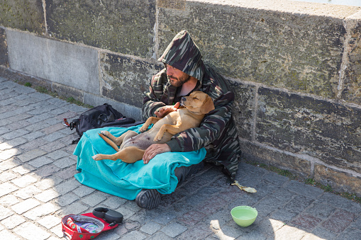 City Prague, Czech Republic. On the street the beggar with dog treats people for money. 2019. 24. April. Travel photo.