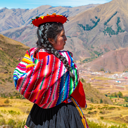 A Quechua indigenous woman looking over the Sacred Valley of the Inca in the archaeological site of Tipon, Andes mountain range, Cusco, Peru.