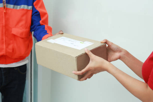 istock Young woman receiving parcel from messenger at home. 1146596784