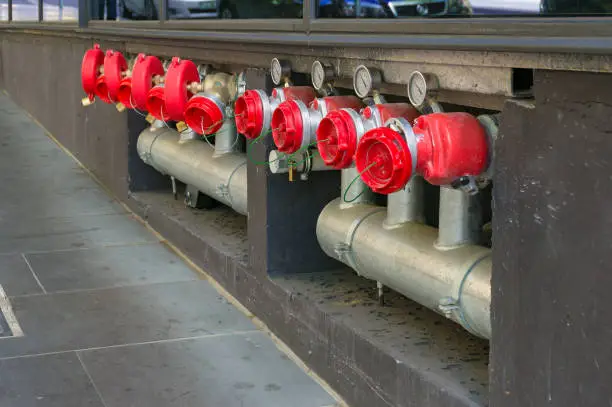 Photo of Bright red hydrant booster valves with metal pipes and red caps