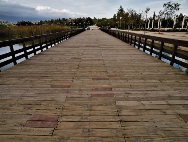 Pedestrian wooden blocks bridge in a park , perspective photo. Bridge above lake in a park. Tritsis enviromental park in Athens Greece.