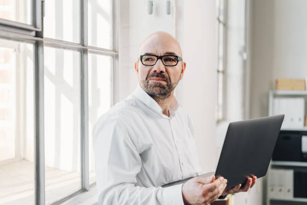 istock Businessman standing holding an open laptop 1146606530