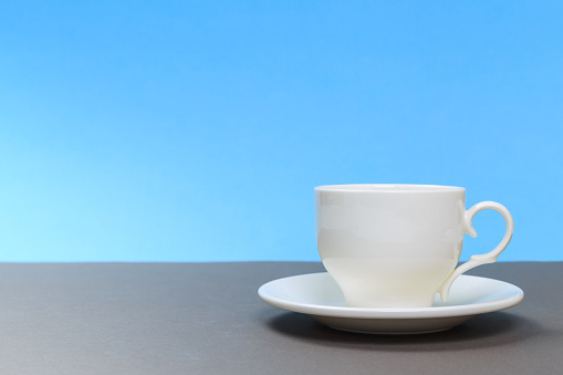 classic  white porcelain tea cup on gray board and blue background