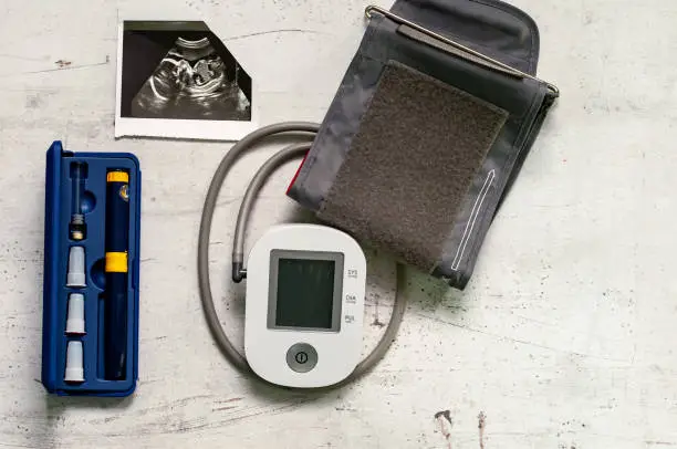 Photo of Ultrasound picture of the 20th week of pregnancy and a blood pressure monitor. Concept of danger of pregnancy and IVF.