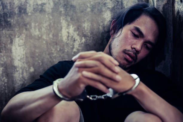 istock Prisoner young asian man get depressed, sad and thinking future life. Bad guy is cuffed and sit in jail or prison. Bad guy get sadness. He don't want to do something wrong but he did because of anger 1146609239