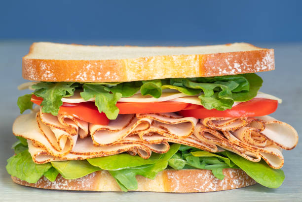 istock Freshly made deli style sandwich with lettuce, several different kinds of vegetables, tomatoes, cheese, meats similar to ham, chicken or turkey. 1146609299