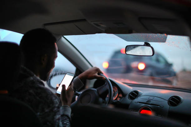 african man using his phone while driving in the rain. - careless imagens e fotografias de stock