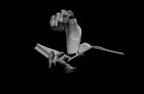A man tears pages from a book in black and white.