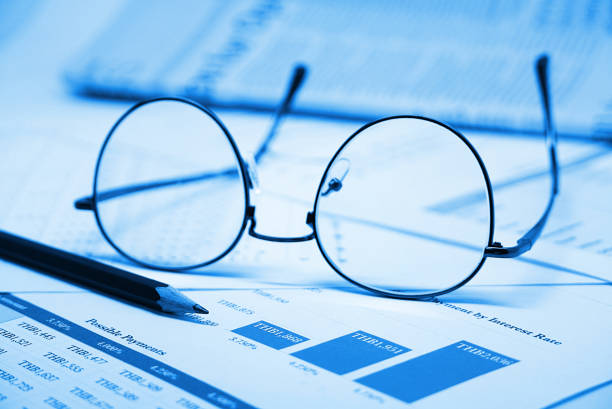 istock Blue theme overlay on eyeglasses and pencil which and finance document on working table 1146615432