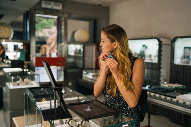 Young woman smiles while trying on jewellery She stands in a jewellery store jewelry store stock pictures, royalty-free photos & images