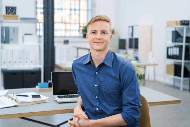 jeune homme d'affaires détendu amical dans le bureau - one young man only photos et images de collection