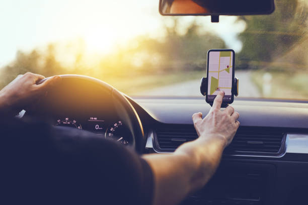 Driver using GPS navigation in mobile phone while driving car Driver using GPS navigation in mobile phone while driving car at sunset dashboard vehicle part photos stock pictures, royalty-free photos & images