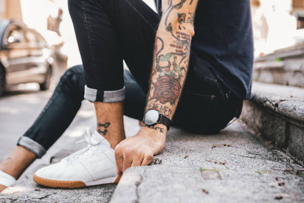 молодой человек носить аналоговые часы - arm tattoo стоковые фото и изображения