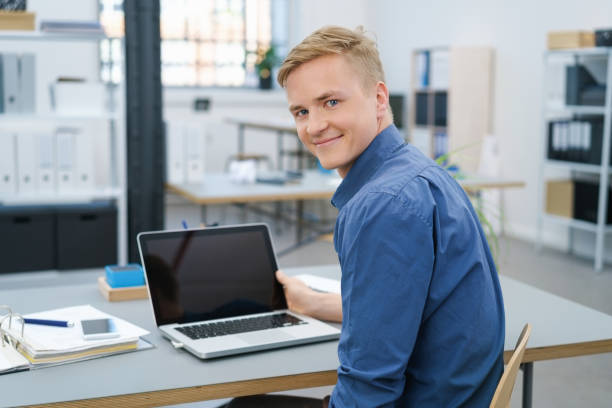 Friendly young businessman working at a laptop