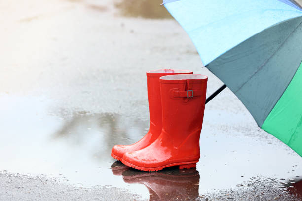 istock Red rubber boots with umbrella in puddle after rain 1146641846