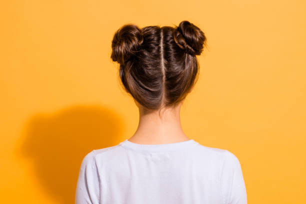 rückansicht aus nächster nähe foto von netter, angenehmer junger frau in weißer kleidung, die ihren neuen haarschnitt von friseurin isoliert über lebhaft gelben hintergrund - rear view women back back of head stock-fotos und bilder