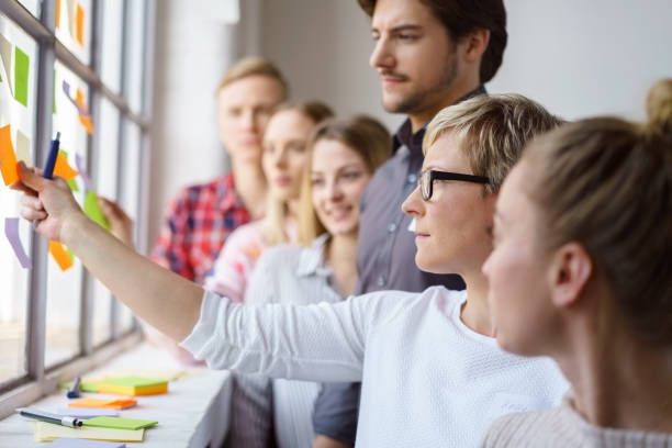 work colleagues discussing ideas with sticky notes - meeting community manager business imagens e fotografias de stock