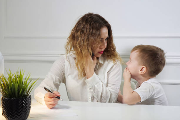 istock Little boy is stopping his mom to work while she is calling phone in her workplace in office. Working mother. 1146646151