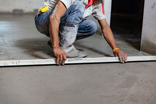 El técnico de construcción está trabajando al nivelar el piso de hormigón para ser liso. photo