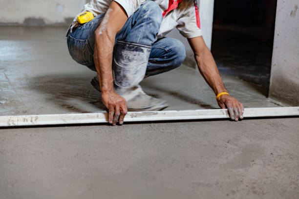 The construction technician is working by leveling the concrete floor to be smooth.