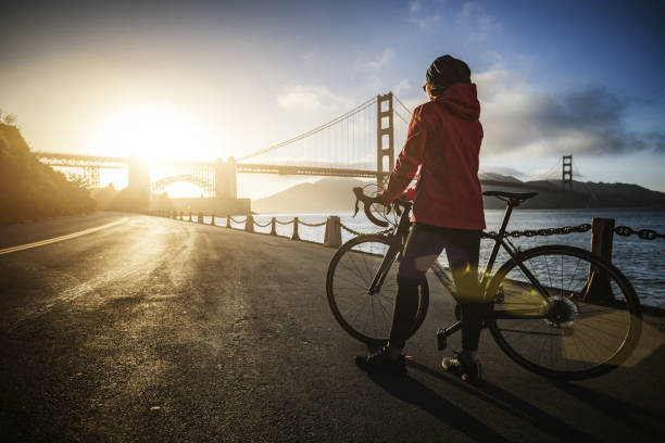 mujer con bicicleta de carreras de carretera y puente golden gate - bridge road city golden gate bridge fotografías e imágenes de stock