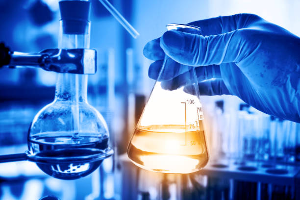 istock Flask in scientist hand with lab glassware background in laboratory. Science or chemical research and development concept. 1146649044