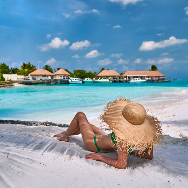 istock Woman sitting on beach under palm tree 1146651259