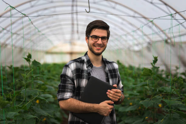 istock Happy farmer with laptop in greenhouse 1146658231