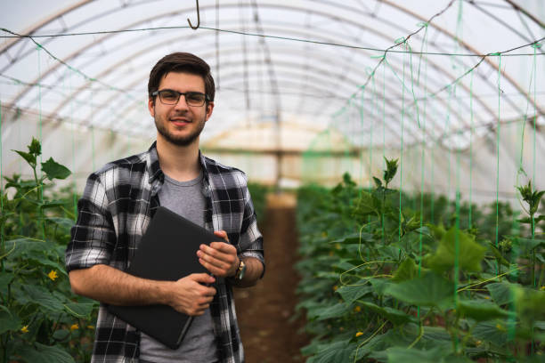 Young farmer with laptop is looking at camera