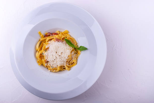 istock Classic Carbonara pasta, spaghetti with pancetta, bacon, egg, parmesan cheese and green arugula on white background. 1146660310