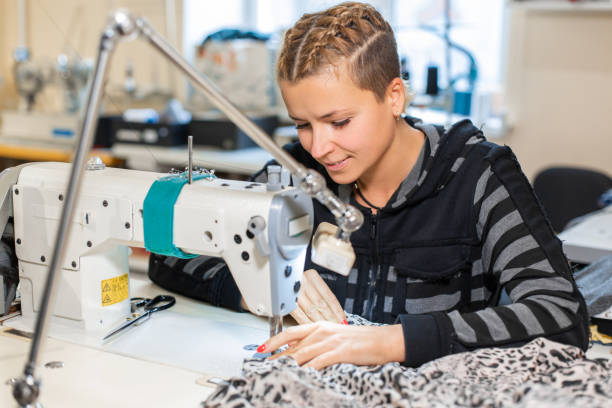 istock Seamstress sewing at machine, portrait. Female tailor stitching material at workplace. Preparing fabric for clothes making. Tailoring, garment industry, designer workshop concept. 1146664977