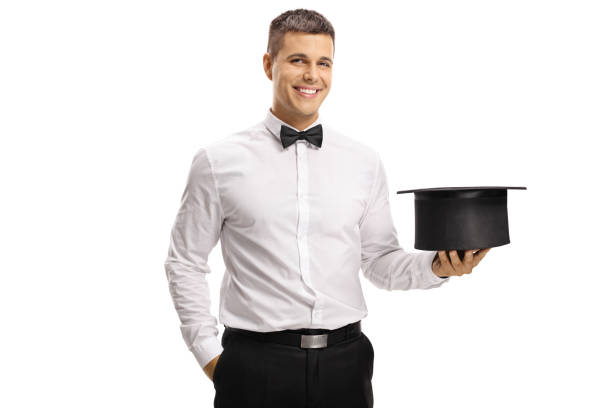 Cheerful magician holding an empty hat and smiling at the camera isolated on white background
