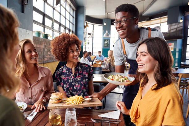 grupo do serviço do empregado de mesa da reunião fêmea dos amigos para bebidas e alimento no restaurante - waiter - fotografias e filmes do acervo