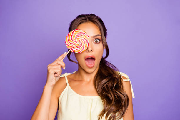 Closeup photo portrait of single charming gorgeous nice glad positive optimistic crazy she her lady holding colorful round red and white candy isolated violet background Closeup photo portrait of single charming gorgeous nice glad positive optimistic crazy she her lady holding colorful round red and white candy isolated violet background. eye candy stock pictures, royalty-free photos & images