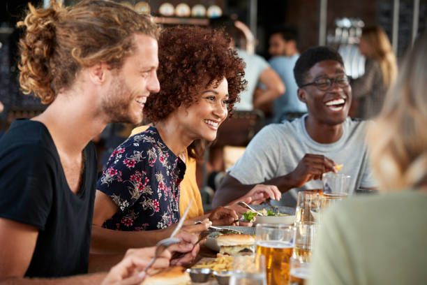 gruppo di giovani amici che si incontrano per bevande e cibo al ristorante - friendship drinking beer group of people foto e immagini stock