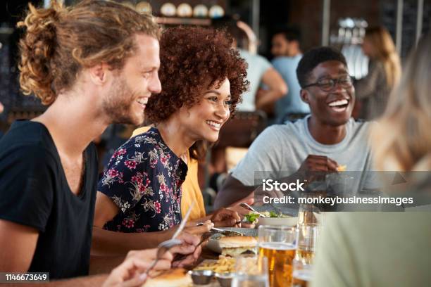 Group Of Young Friends Meeting For Drinks And Food In Restaurant Stock Photo - Download Image Now