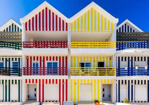 Photo of Street with colorful houses in Costa Nova, Aveiro, Portugal. Street with striped houses, Costa Nova, Aveiro, Portugal. Facades of colorful houses in Costa Nova, Aveiro, Portugal.