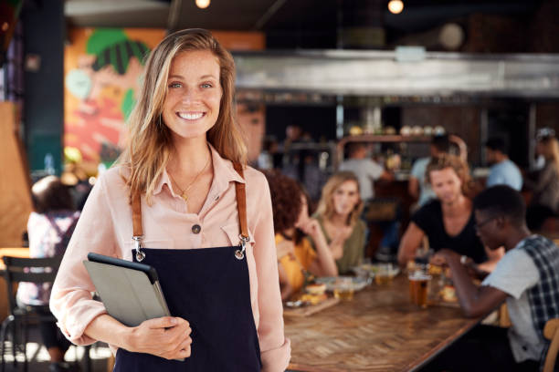 porträt der waitress holding menus serving in busy bar restaurant - waitress stock-fotos und bilder