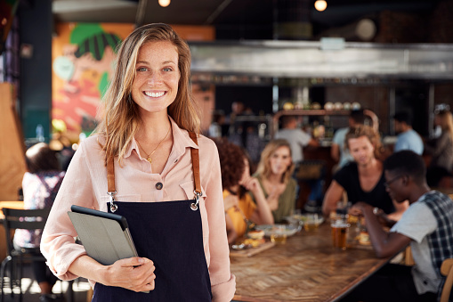 Retrato de mesera que sostiene menús sirviendo en el concurrido bar restaurante photo
