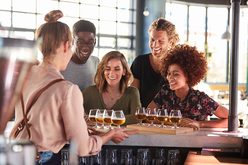 Camarera sirviendo grupo de amigos degustación de cerveza en bar photo