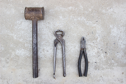 Sledge hammer, tongs, pliers, on concrete. Blacksmith tools, top view.