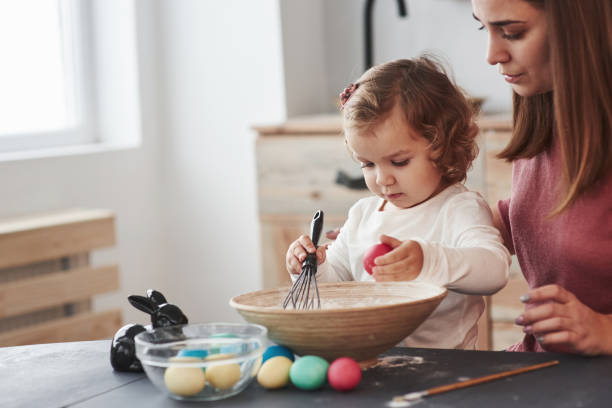 полностью сконцентрирован на работе. мать учит дочь рисовать яйца на пасхальные праздники - vacations two generation family holiday easter стоковые фото и изображения