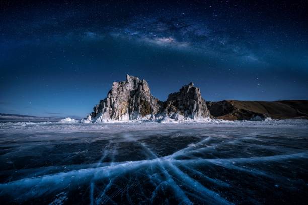 paysage de la roche de shamanka et voie lactée sur le ciel avec la glace cassante naturelle dans l’eau gelée sur le lac baïkal, sibérie, russie. - lake night winter sky photos et images de collection