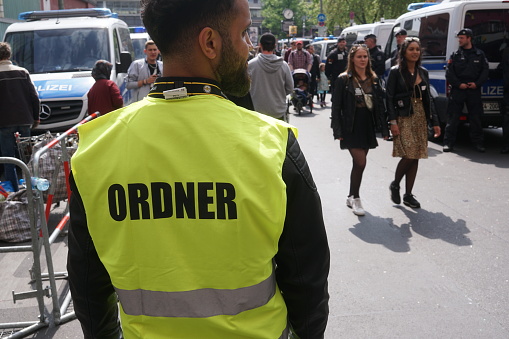 Berlin, Germany - May 1, 2019: Back turned security officer wearing a yellow vest