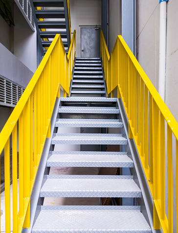 Metal fire escape with the yellow ladder on the office building.