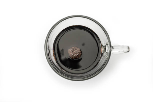 Black coffee with bubbles in glass cup on a white background, high angle view
